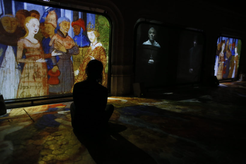 Femme regardant les projections de la visite libre de l'Historial Jeanne d'Arc